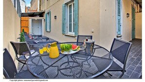 Ein Essbereich im Freien mit einem runden Metalltisch, Stühlen und einer Wassermelone auf einem Teller.