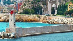A coastal scene with a lighthouse, rocky breakwater, and a historic archway. - SunlightProperties AMOUR VIOLETTE: Hyper Center, 2 bedroom apt with terrace (Nice)