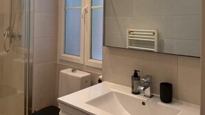 A bathroom with a glass shower enclosure, a white sink, and a towel rack. - SunlightProperties AMOUR VIOLETTE: Hyper Center, 2 bedroom apt with terrace (Nice)