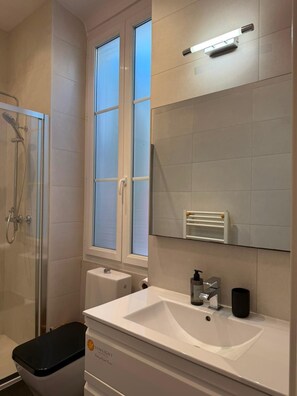 A bathroom with a glass shower enclosure, a white sink, and a towel rack. - SunlightProperties AMOUR VIOLETTE: Hyper Center, 2 bedroom apt with terrace (Nice)