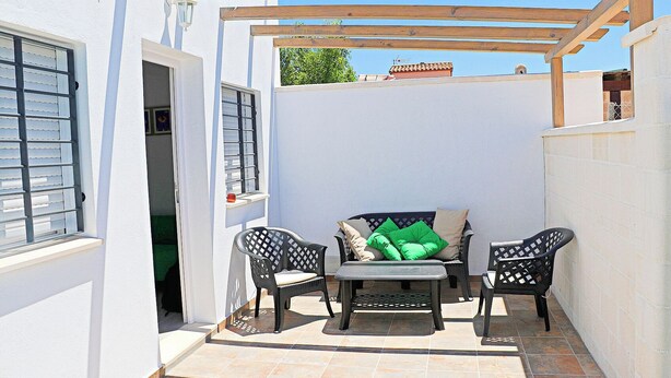A patio area with a pergola, two chairs, a table, and a bench with cushions. - Rural apartment for four people (CONIL DE LA FRONTERA)