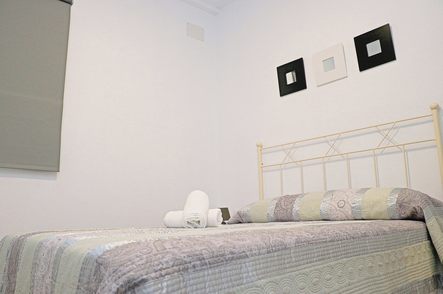 Camera da letto con un letto, una testiera e tre interruttori della luce fissati al muro.