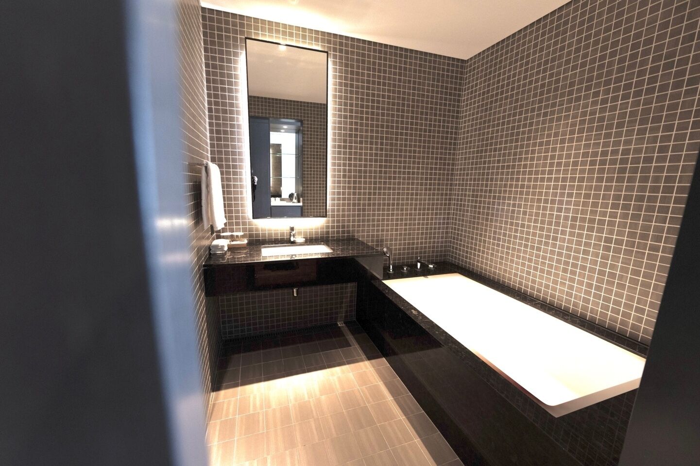 Un baño moderno con un lavamanos rectangular, un espejo grande y una bañera.