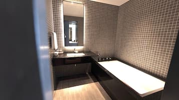 Un baño moderno con un lavamanos rectangular, un espejo grande y una bañera.