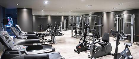 A modern gym with treadmills, elliptical machines, and weight equipment.