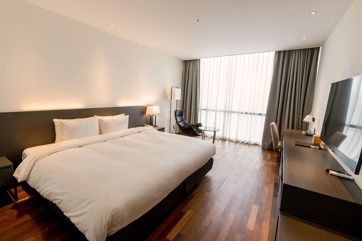Ett modernt hotellrum med en stor säng, ett skrivbord med en platt-TV och en stol.