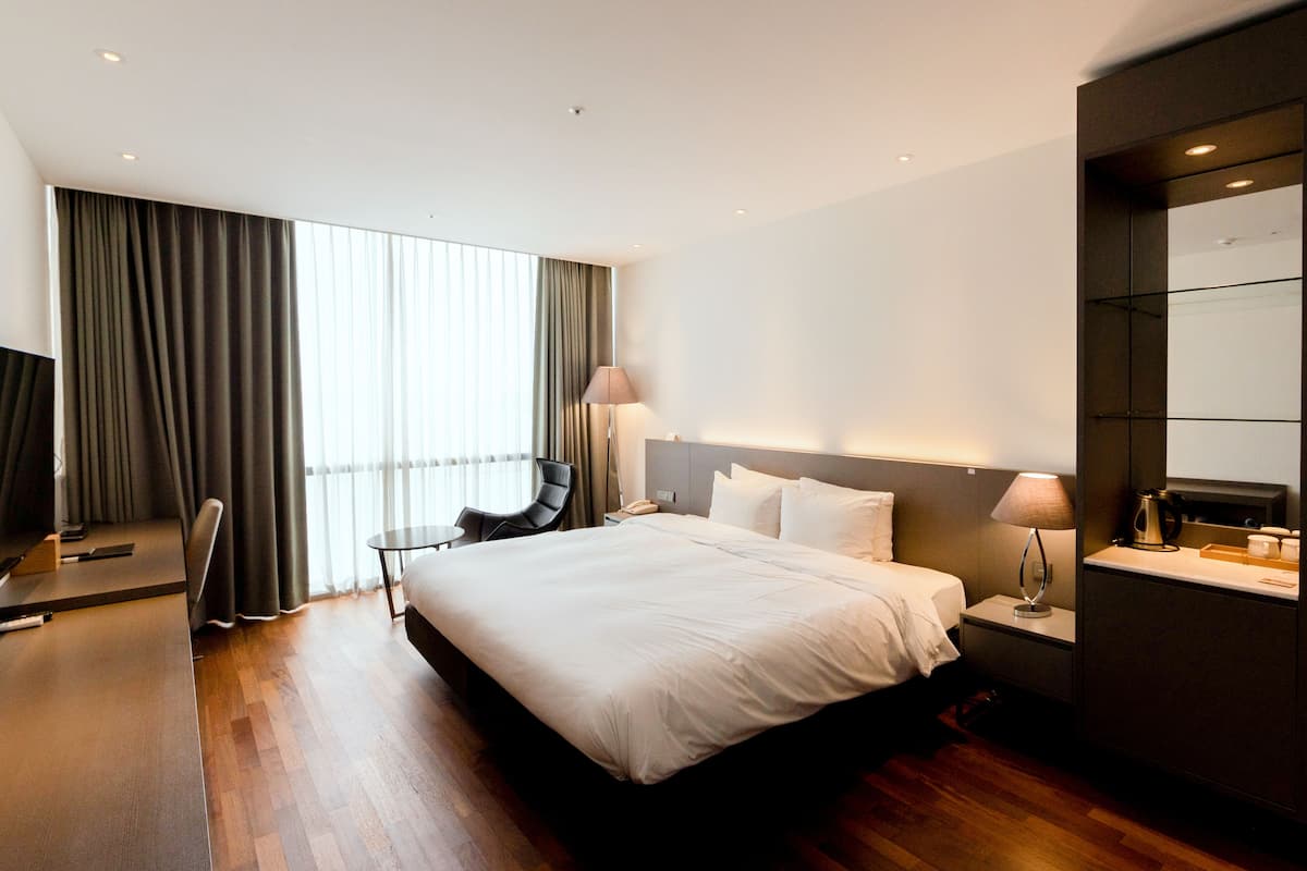 Ett modernt hotellrum med en stor säng, ett skrivbord, en stol och en tv.