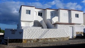 A white building with a tiled roof, a stone base, and a signboard. - Attic apartment with stunning sea views (Costa Calma (Fuerteventura))