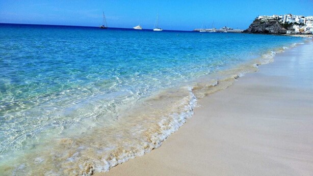 A beach with clear turquoise water, a sandy shore, and boats in the distance. - Attic apartment with stunning sea views (Costa Calma (Fuerteventura))
