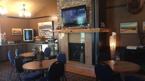 Un comedor acogedor con chimenea, un televisor montado arriba y una zona de bar con microondas y refrigerador.