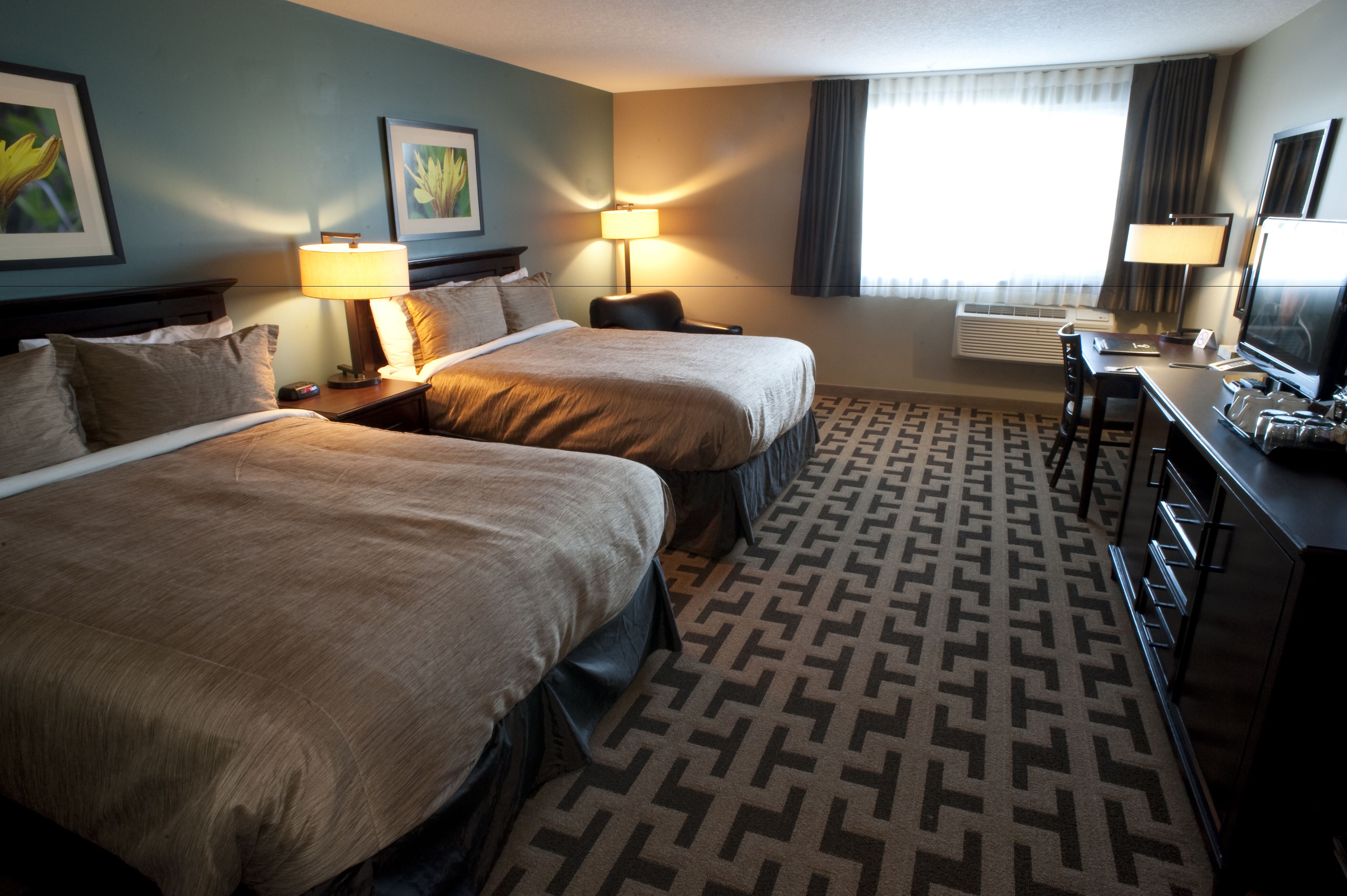Une chambre d’hôtel avec deux lits, un bureau, une chaise et un téléviseur.