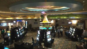 Un casino con múltiples mesas de juego y una estructura decorativa central.