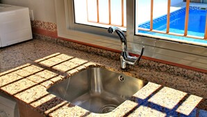 A kitchen with a stainless steel sink, granite countertop, and a window with a view of a pool. - Villa with private pool in rural area (CONIL DE LA FRONTERA)