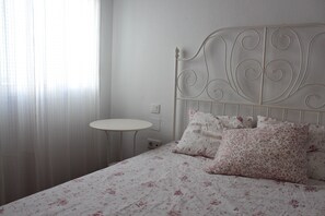 Ein Bett mit floralem Bettzeug, ein runder Tisch und ein weißer Kopfteil.