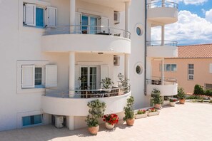 A multi-story building with balconies, potted plants, and a clear sky.