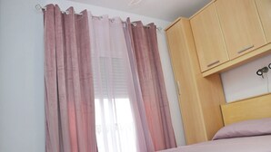 Ein Schlafzimmer mit einem Bett, einem Holzschrank und rosa Vorhängen.