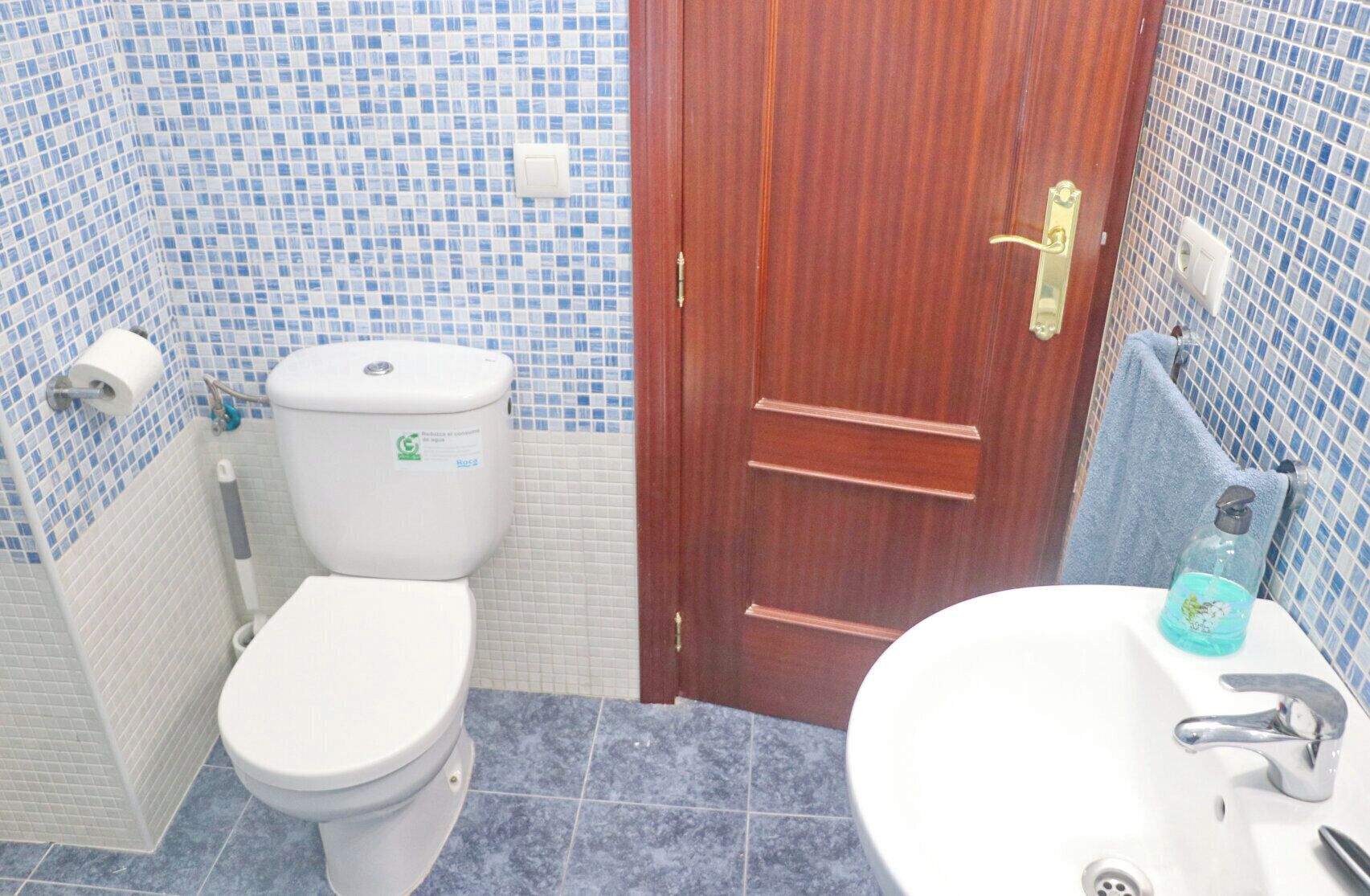 Un baño con inodoro, lavamanos y puerta de madera.