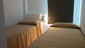 Une chambre avec deux lits, une table de chevet et une fenêtre.