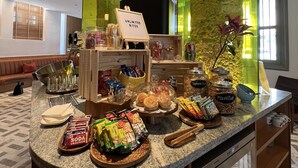 Buffet-alueella on monipuolinen valikoima ruokia, kuten purkkeja, joissa on sekoitettuja pähkinöitä ja pikkupurtavaa, kulho täynnä hedelmiä sekä kyltti, jossa lukee: ”Syö niin paljon kuin haluat”.