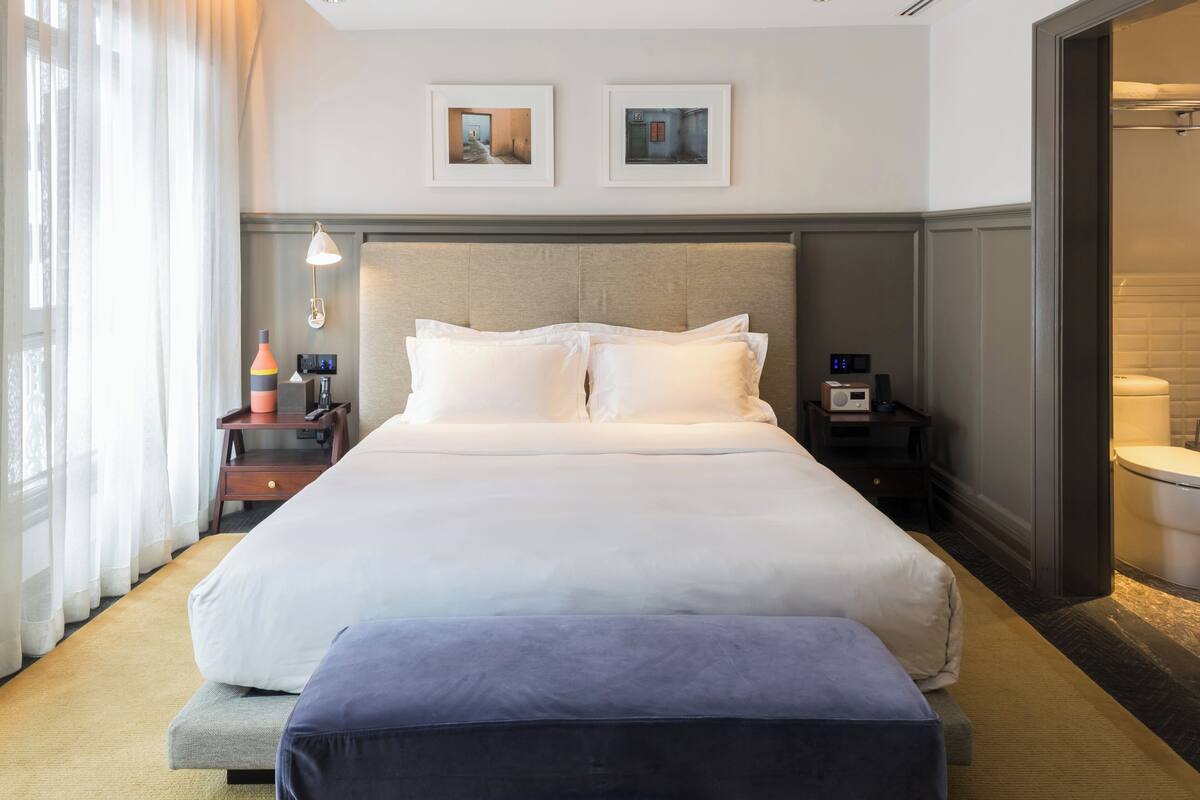 A hotel room with a large bed, bedside tables, a lamp, and framed pictures on the wall.