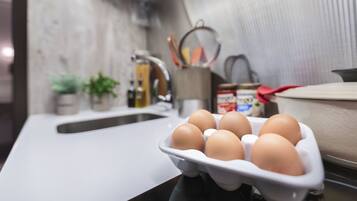 Una encimera de cocina con un cartón de huevos, un fregadero y varios utensilios de cocina.