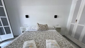 Habitación de hotel con cama, dos mesitas de noche, un armario y dos toallas con un logo.