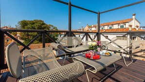A balcony with wicker furniture and a table set with a drink and flowers.