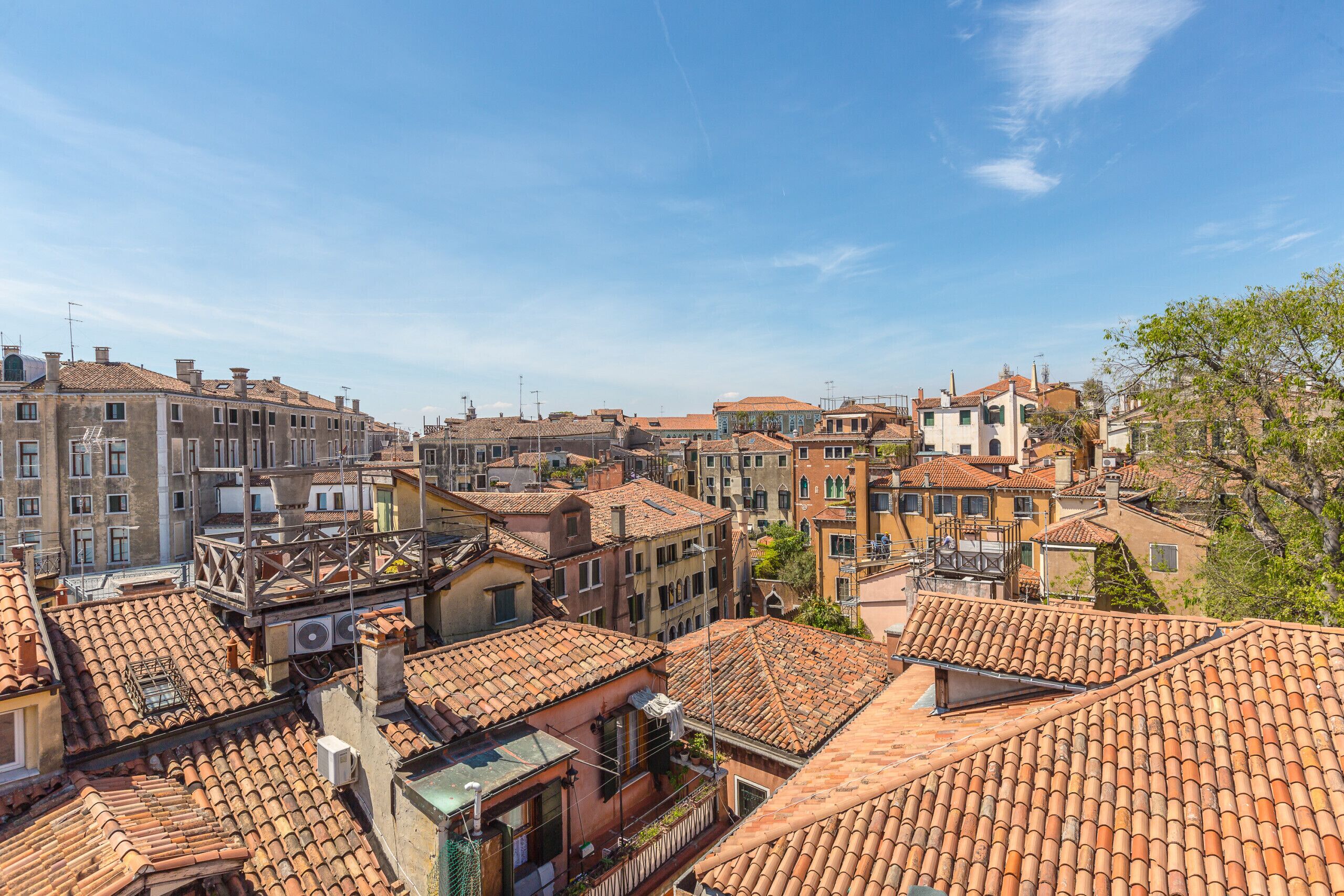 Une zone urbaine densément peuplée, caractérisée par des toits recouverts de tuiles en terre cuite, une variété de styles architecturaux et un ciel dégagé.