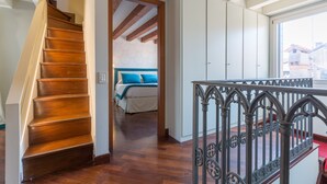 A staircase leading to a bedroom with a bed, a window, and a wardrobe.