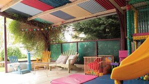 A covered outdoor area with a slide, seating, and a play structure.