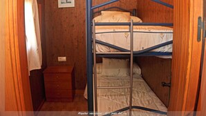 A small, wooden room with a bunk bed, a wooden dresser, and a small table.