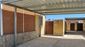 A covered outdoor area with a stone wall, a wooden door, and a metal roof.