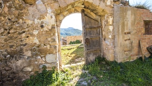 Un arc en pierre d’époque, menant à un bâtiment rustique doté d’une porte en bois.