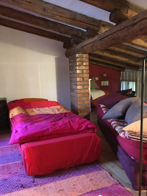 Quarto aconchegante com cama, sofá e teto de madeira.