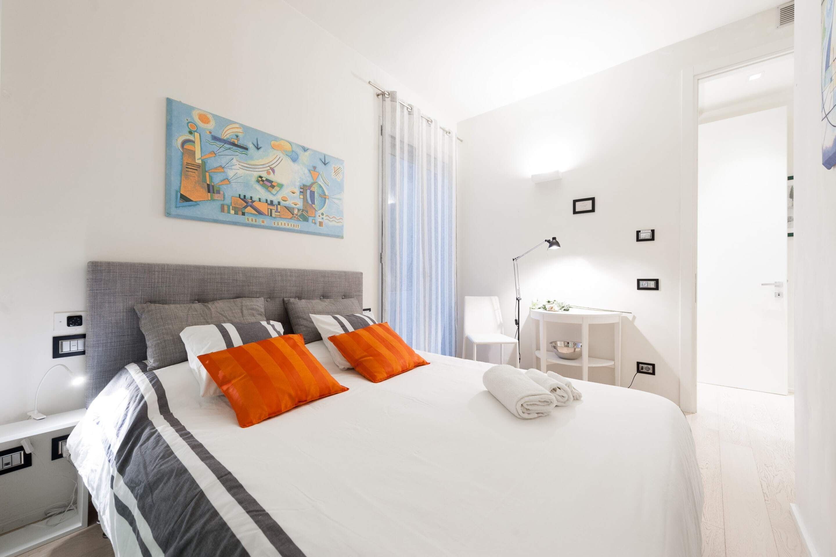 Une chambre d’hôtel moderne, dotée d’un grand lit, d’un bureau et d’une chaise.