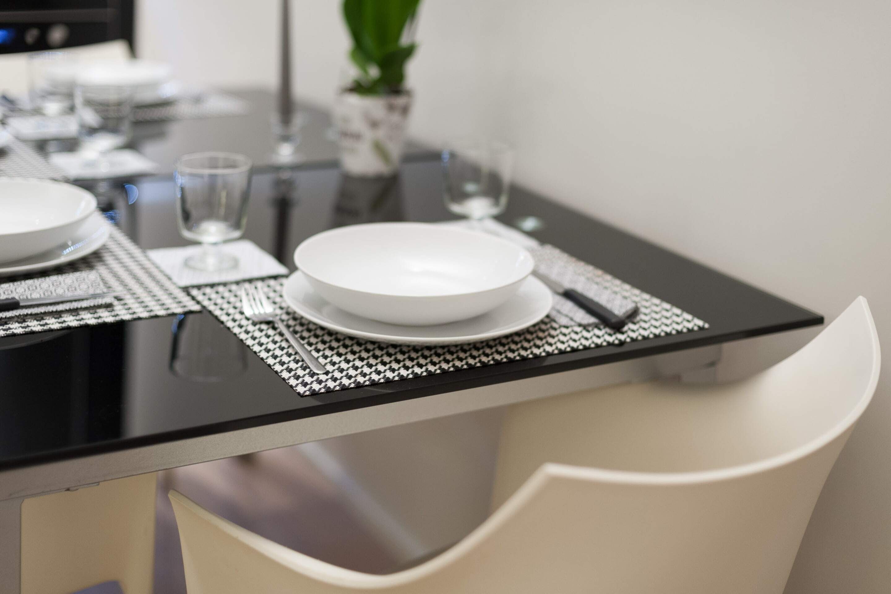 A dining table with plates, glasses, and cutlery set on a black tablecloth.