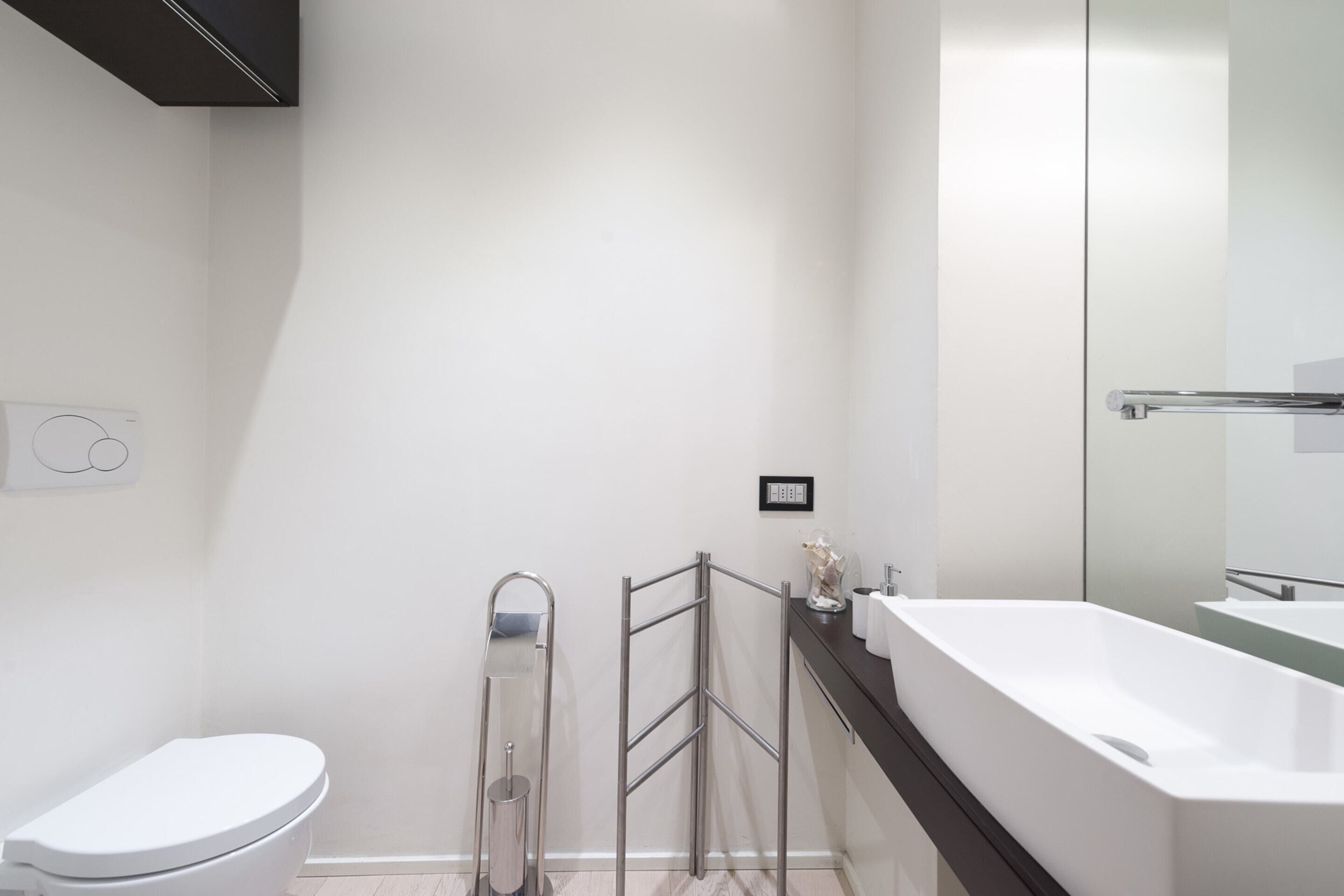 A modern bathroom with a white toilet, a glass shower enclosure, and a large white bathtub.