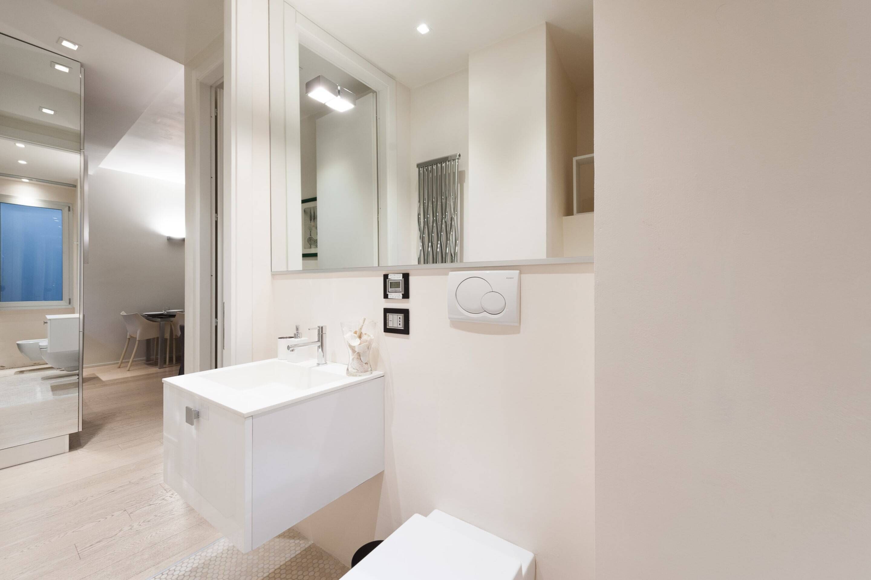 Une salle de bain moderne avec un grand miroir, un lavabo blanc et un espace douche.