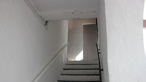 Una escalera con paredes blancas y barandillas negras que conduce a una habitación.