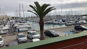 A marina with numerous boats docked, a palm tree, and several parked cars.