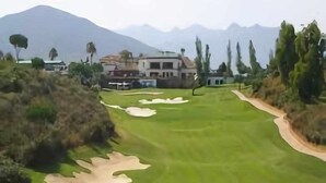 A golf course with bunkers, a clubhouse, and a mountain backdrop. - Balcon Del Mar Primera Linea de Playa (Mijas)