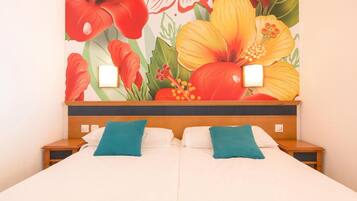 Una habitación de hotel con una cama, dos mesitas de noche y un gran mural floral en la pared.