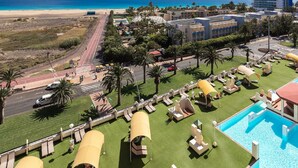 Un resort con piscina, lettini e vista sulla spiaggia e sull'oceano.