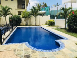 Una piscina al aire libre, sombrillas, sillones reclinables de piscina