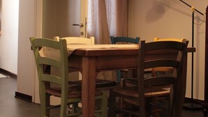 A dining area with a wooden table and chairs, two pendant lights, a wall clock, and a door leading to another room. - FROM IRENE                                                           (Bassano del Grappa)