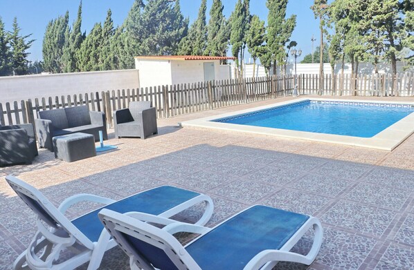 A swimming pool with lounge chairs and a small seating area.