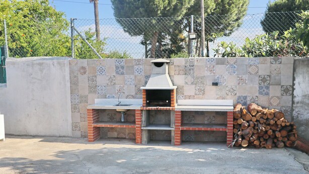An outdoor brick barbecue with a sink and a tiled backsplash.
