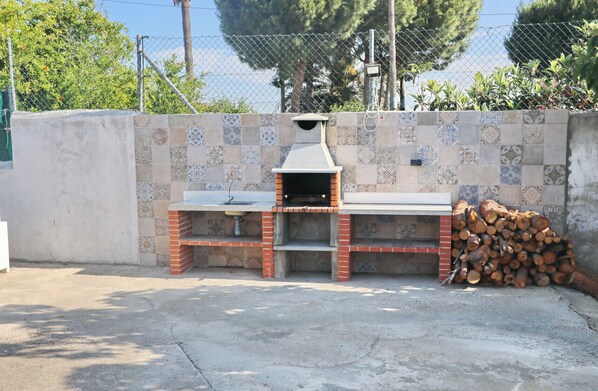 An outdoor brick barbecue with a sink and a tiled backsplash.