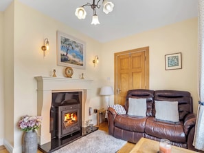 A cozy living room with a fireplace, leather sofa, and a dining table. - Spiddal Cottage (Spiddal)