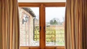Une pièce dotée d’une grande porte-fenêtre à panneaux coulissants en bois, qui donne sur un jardin.